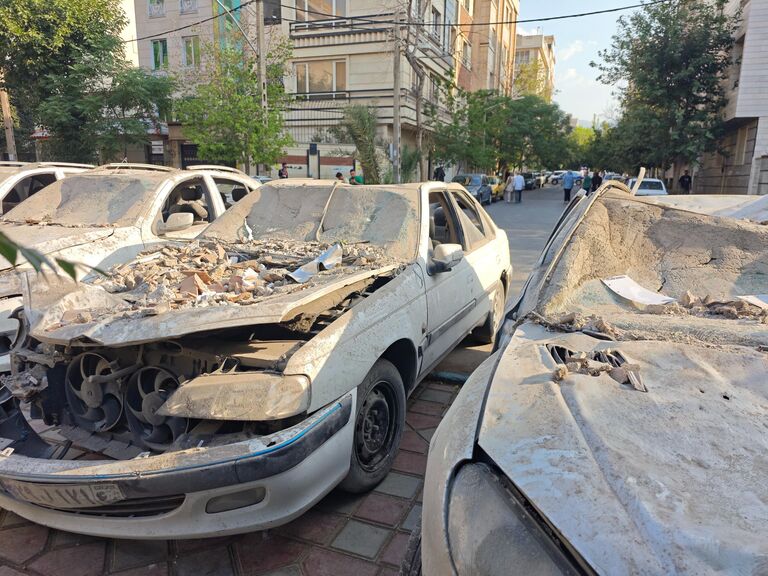 Поврежденные автомобили на площади в районе Нармак в Тегеране после израильских авиаударов