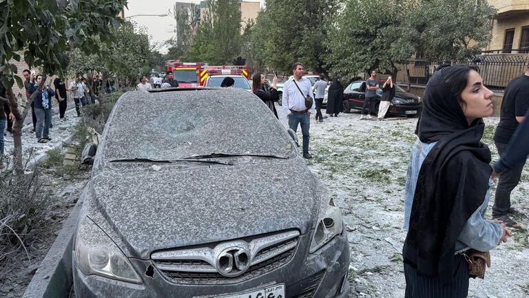 Люди осматривают последствия массированного израильского авиаудара в Тегеране